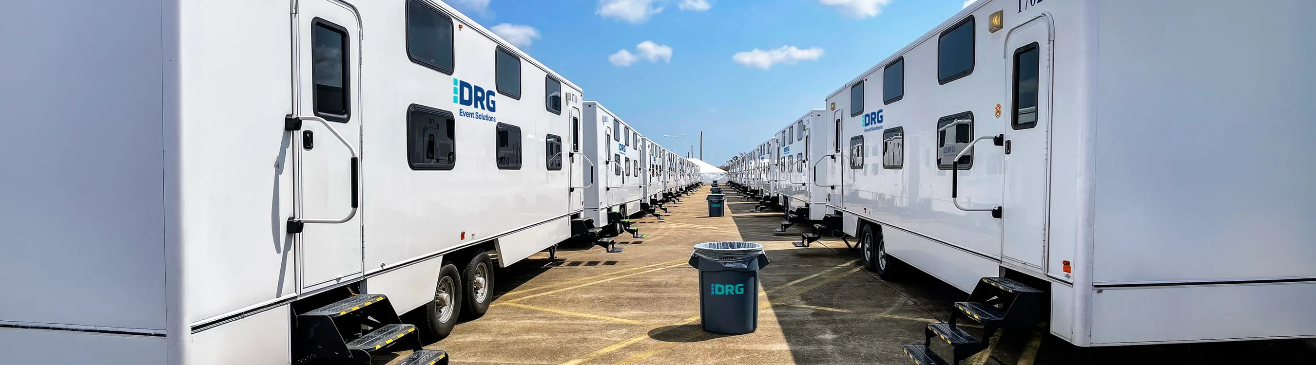 A long aisle between two rows of white DRG sleeper trailers under a blue sky.