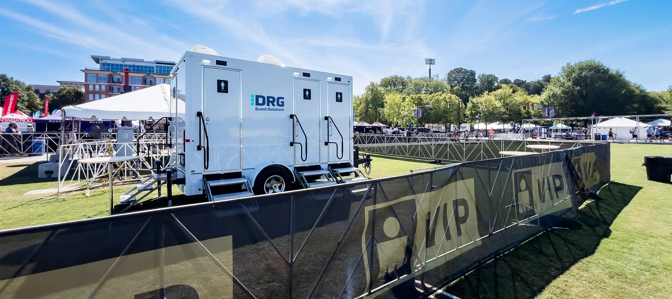 DRG Event Solutions trailers staged beside a VIP area fence at an outdoor event.