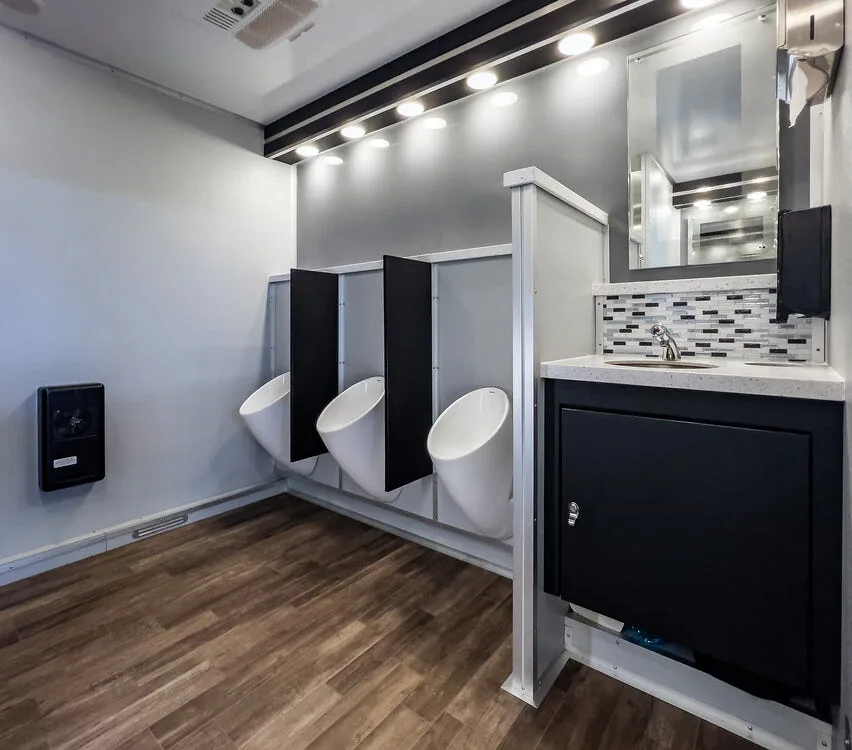 Row of urinals with privacy dividers and a vanity.