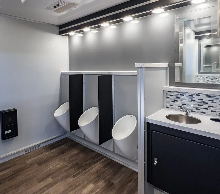 Urinals beside the vanity under LED lighting.