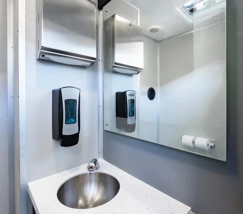 Corner sink with mirror and soap dispenser.