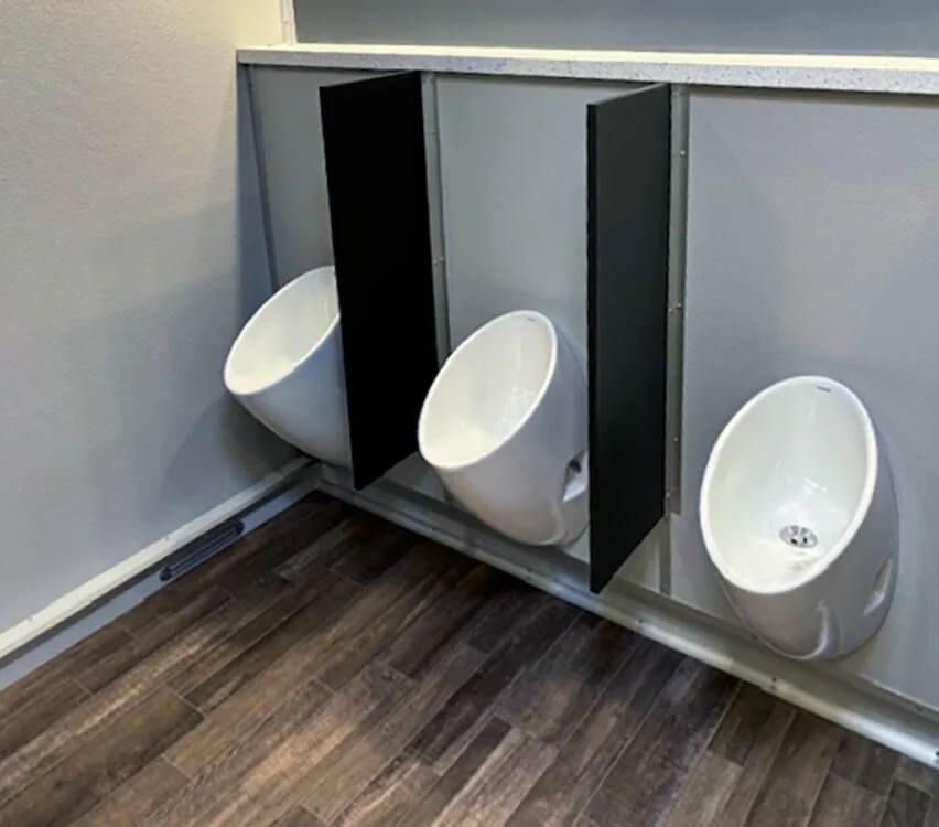 Three urinals with privacy dividers.