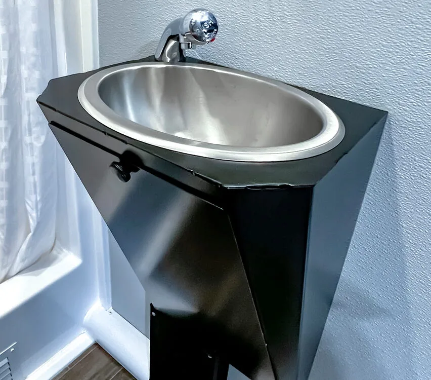 Stainless steel sink with metered faucet.