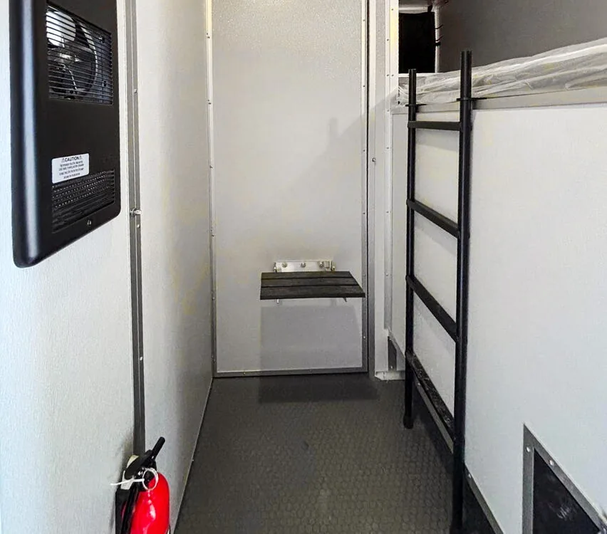 Individual cabin with bunk and fire extinguisher.