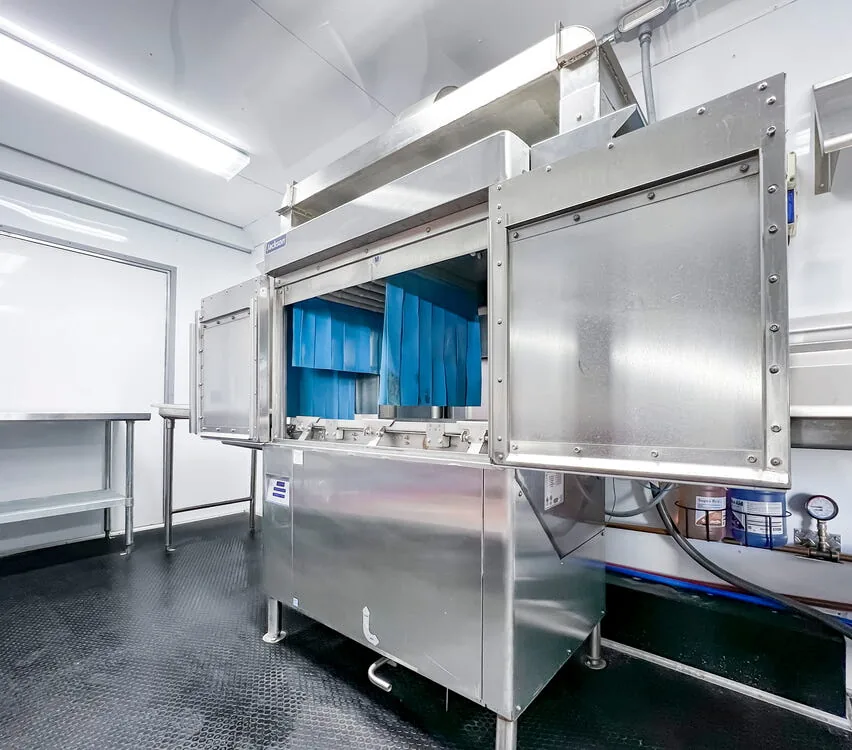 Conveyor dishwashing machine with stainless steel tables.