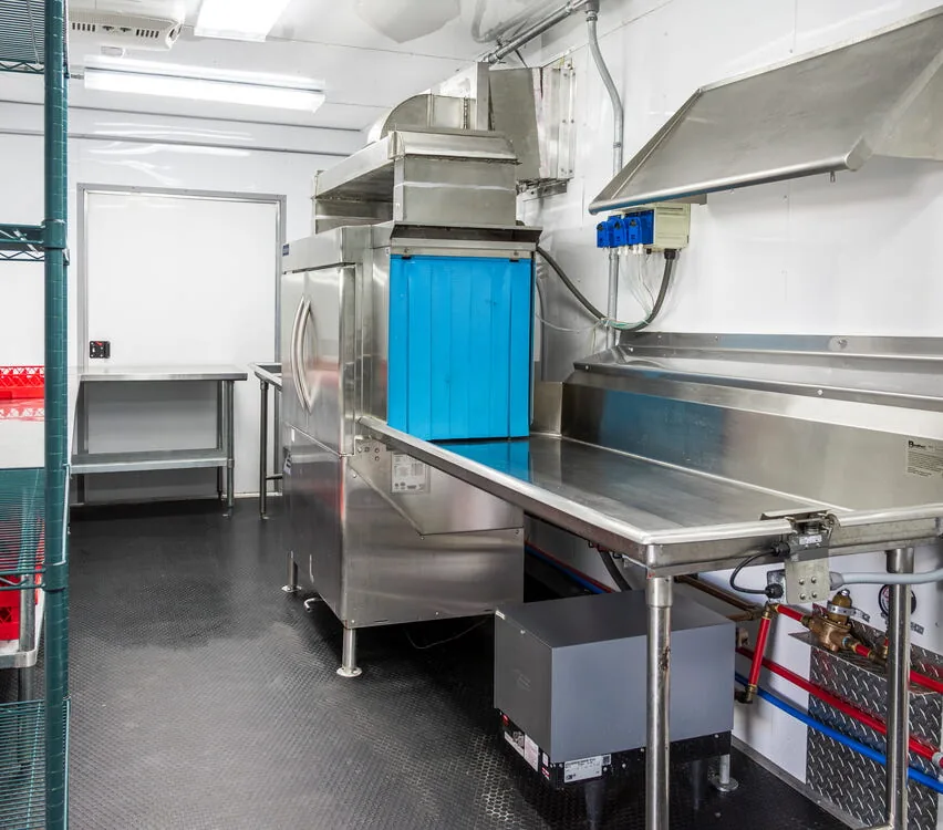 Dish room with wire shelving and dishwashing machine.