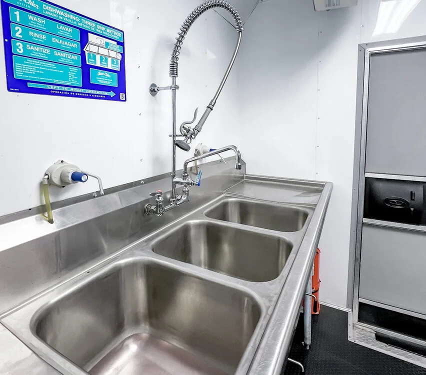 Three-compartment sink with spray faucet.