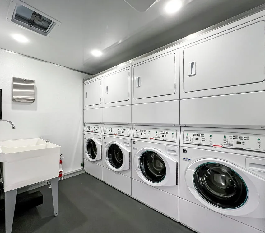 Stacked washers and dryers beside a double sink.
