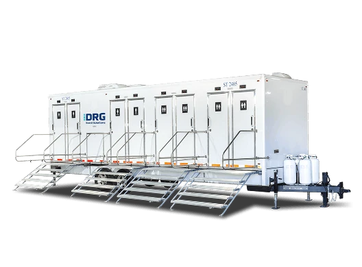 Long white DRG shower trailer with multiple doors and stairs.